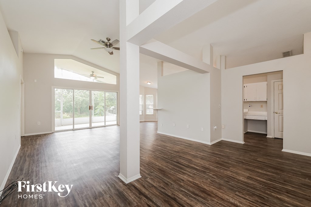 A spacious room with wooden floors and white walls, part of a house by FirstKey Homes.