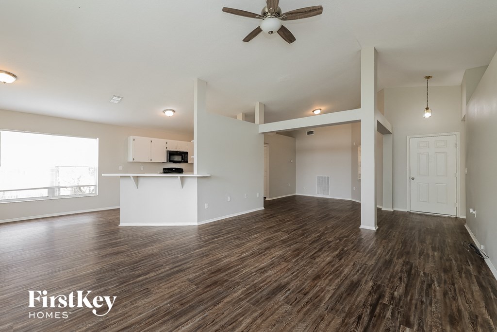 A spacious room with wooden floors and a ceiling fan.