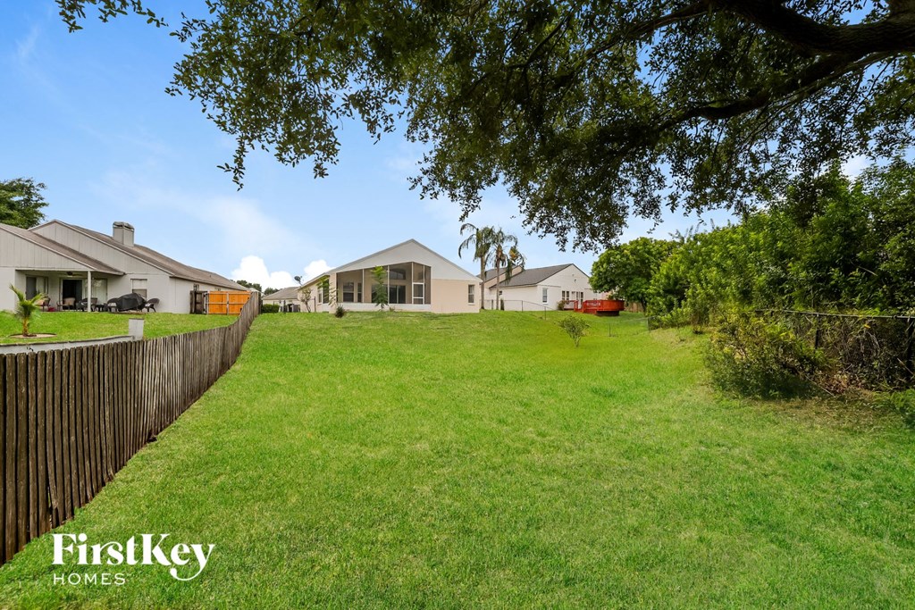 A grassy area with a fence and houses in the background.