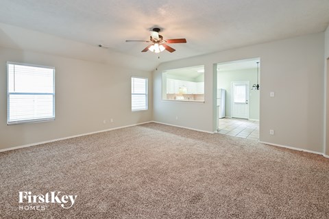 A spacious room with a carpeted floor and a ceiling fan.