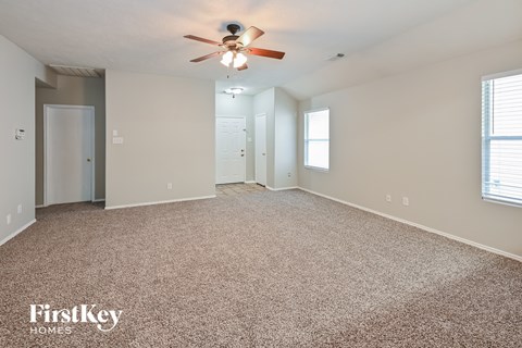 A spacious room with a ceiling fan and carpeted floor.