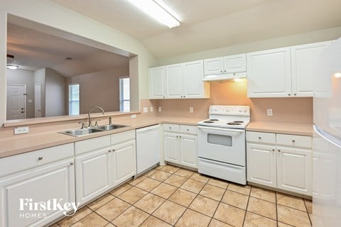 A kitchen with white cabinets and a tiled floor.