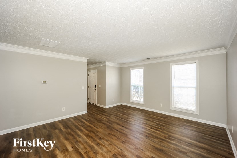 the living room and dining room of a house with wooden floors and white walls