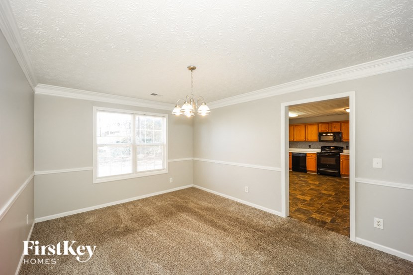 an empty living room with carpet and a kitchen