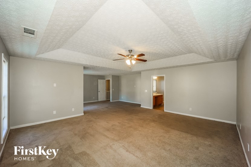 a empty living room with a ceiling fan and a carpet