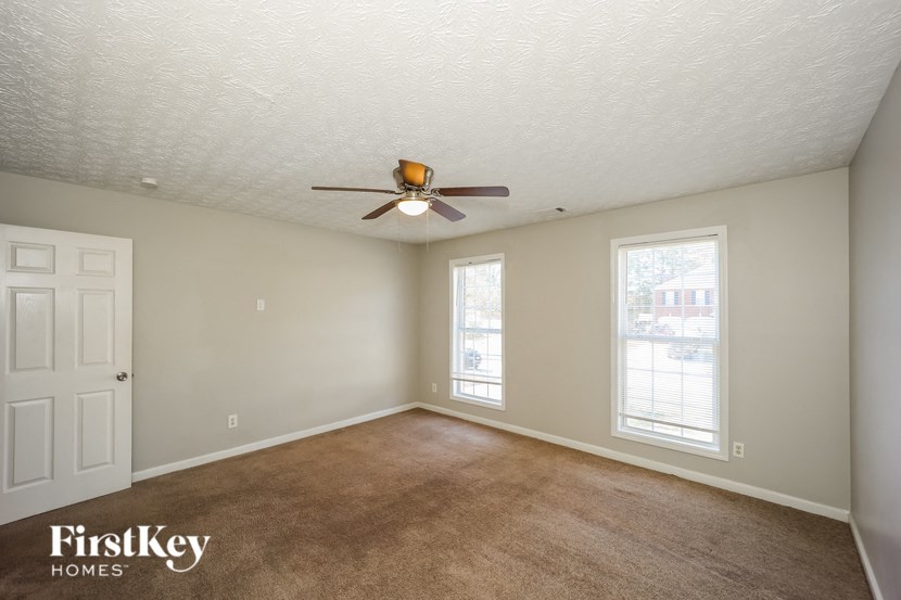 an empty living room with a ceiling fan and a window