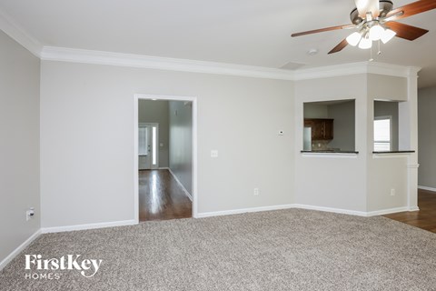 a empty living room with a ceiling fan and a carpet