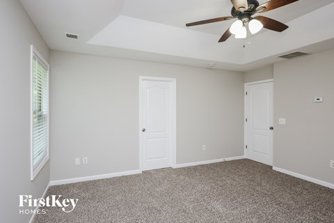 the master bedroom has a ceiling fan and a carpeted floor