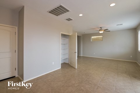 A spacious room with a ceiling fan and a door leading to another room.