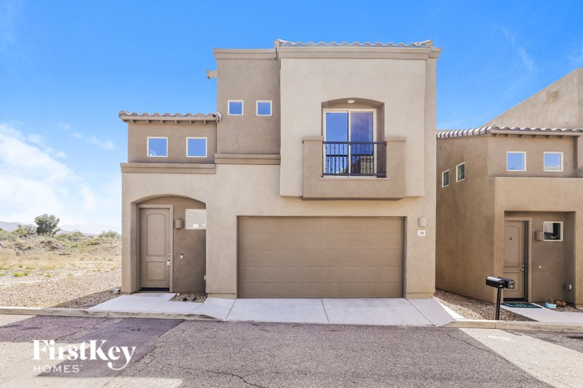 a beige house with a garage door and a sidewalk