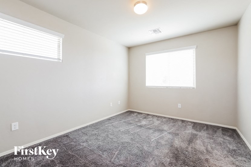 a room with a carpeted floor and two windows