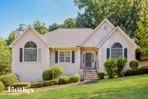 a white house with black shutters and yellow trim and a lawn