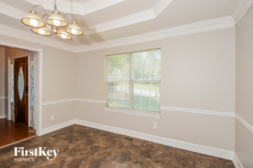 an empty dining room with a window and a chandelier