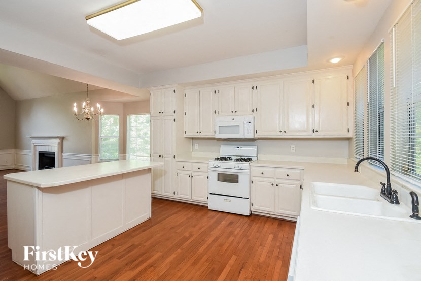 a kitchen with white cabinets and white appliances and a wooden floor