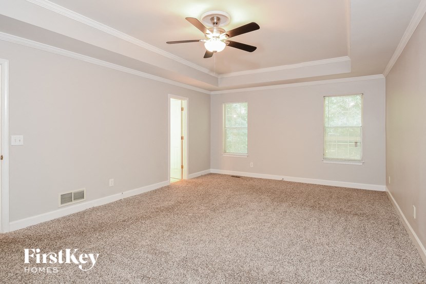 the spacious living room with ceiling fan and carpet