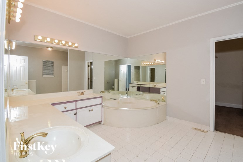 a large bathroom with a tub and a sink and a mirror