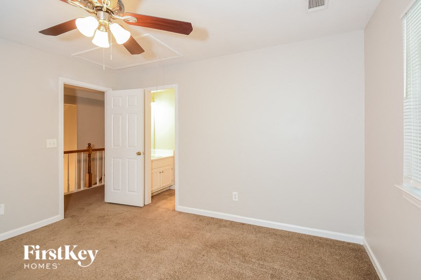 a living room with a ceiling fan and a door to a bathroom