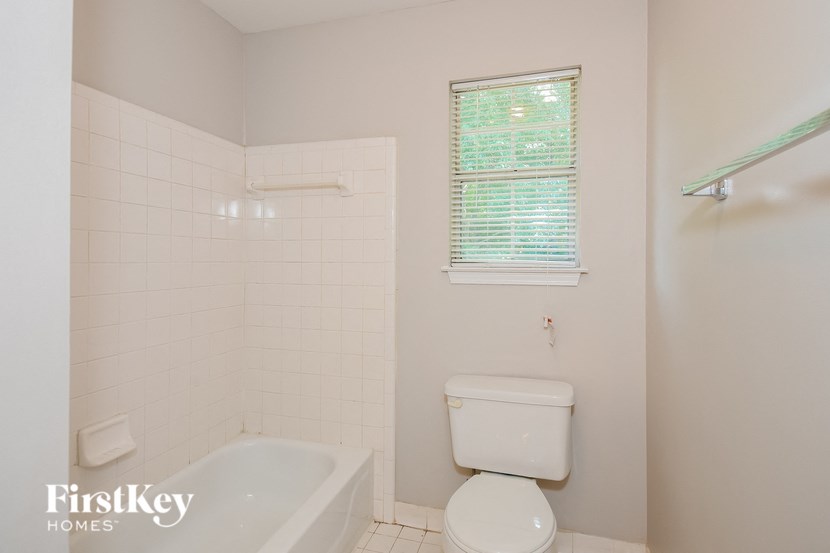 a bathroom with a toilet and a tub and a window