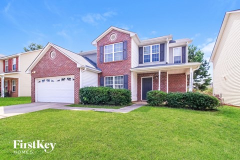 A house with a red brick facade and a white garage door is for sale.