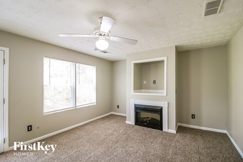 A living room with a fireplace and a ceiling fan.
