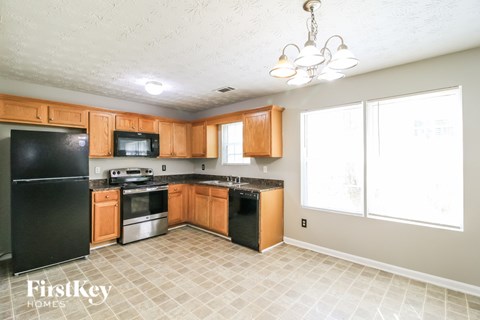 A kitchen with wooden cabinets and a black fridge.