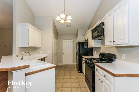 A kitchen with black appliances and white cabinets.