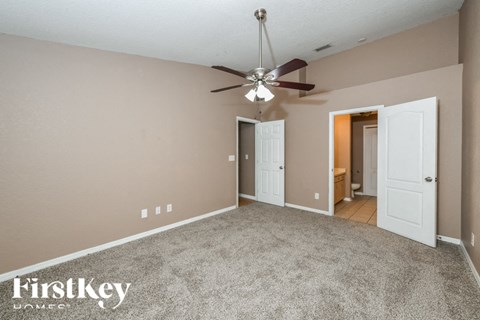 A spacious room with a ceiling fan and two doors.
