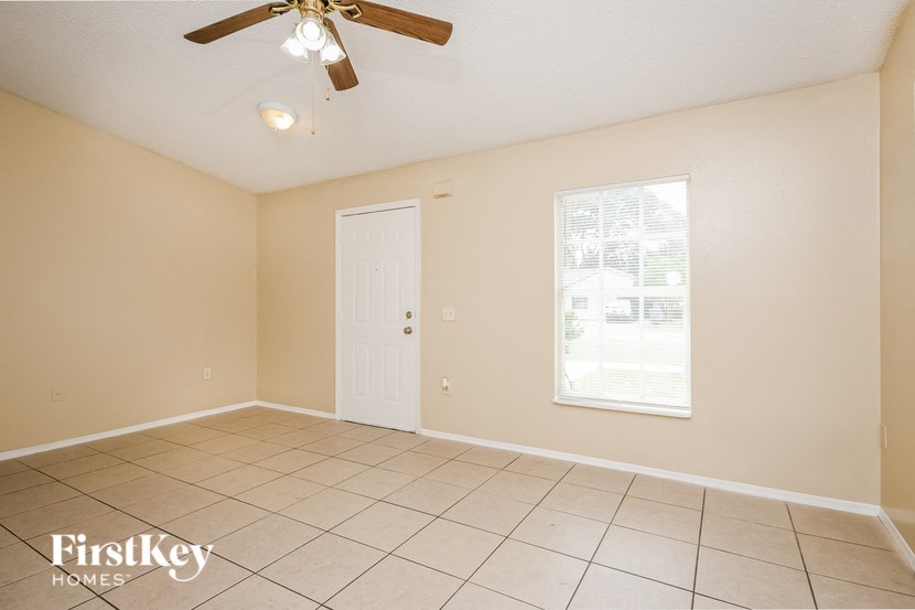 an empty living room with a ceiling fan and tiled floor