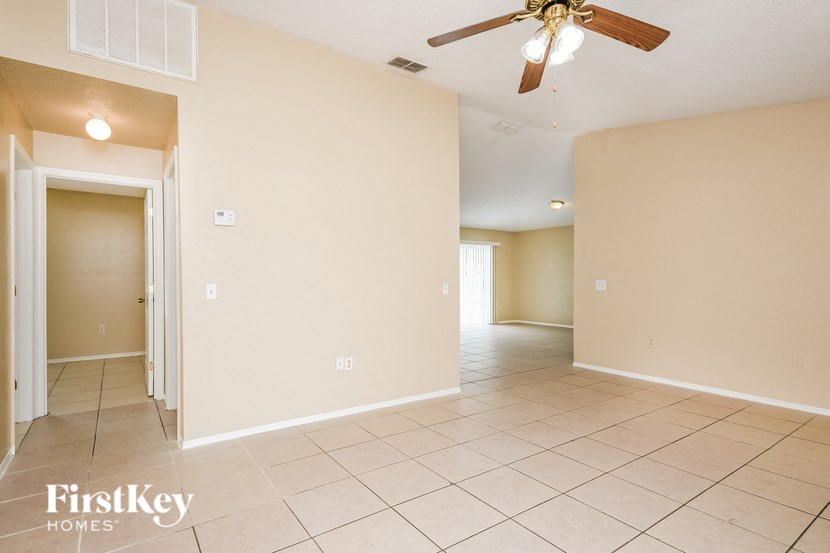 a empty living room with a ceiling fan and tiled floors