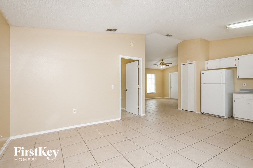 an empty kitchen with white appliances and tiled floors
