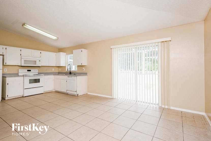 a large kitchen with white appliances and a sliding glass door