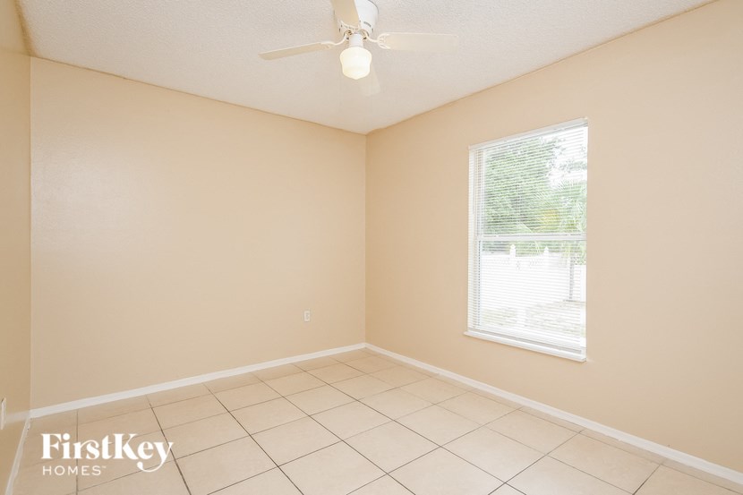 an empty living room with a ceiling fan and a window