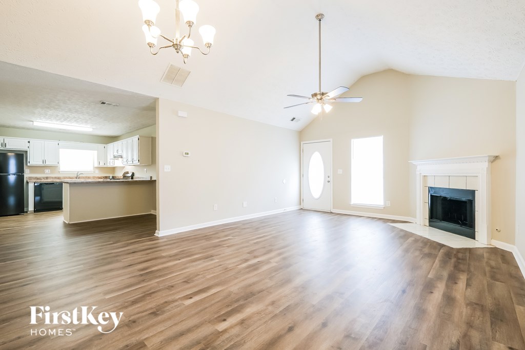 A spacious living room with a fireplace and a ceiling fan.