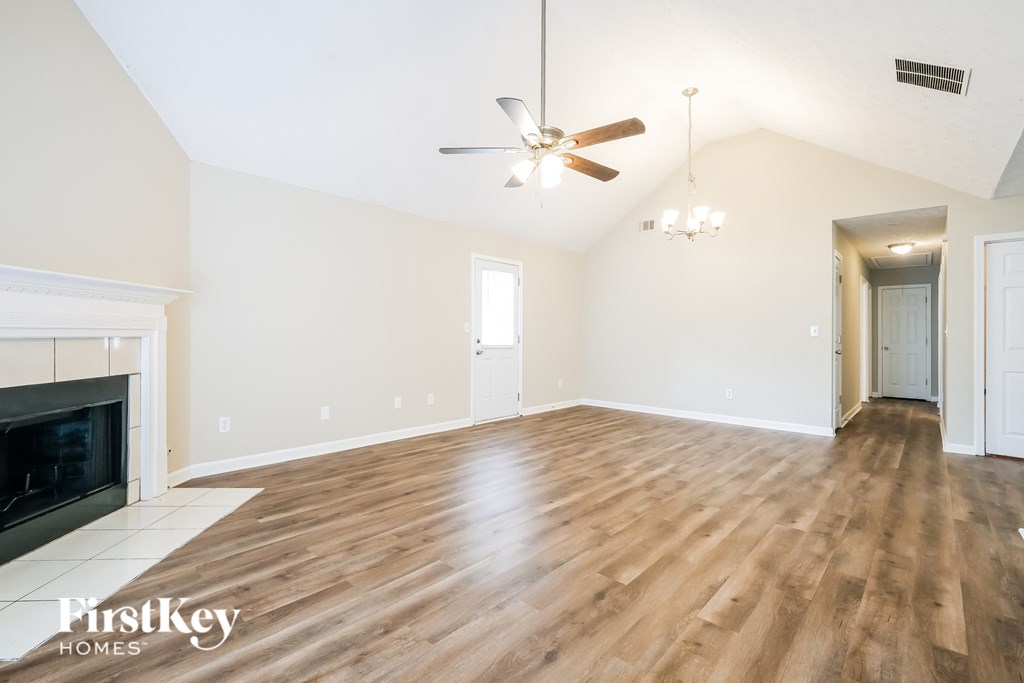 A spacious room with a fireplace and wood flooring.