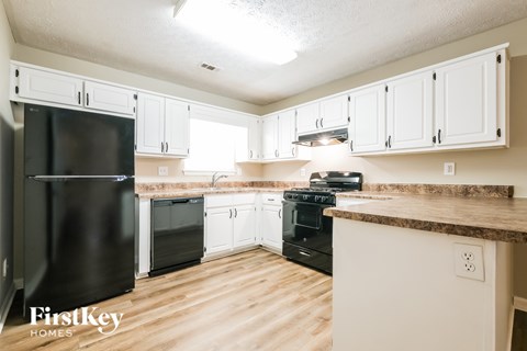 A kitchen with a black fridge and black stove top oven.