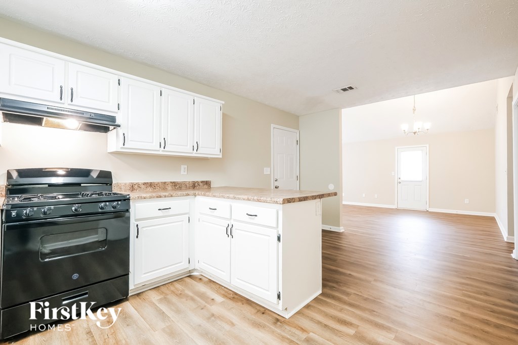 A kitchen with a black stove top oven and white cabinets.