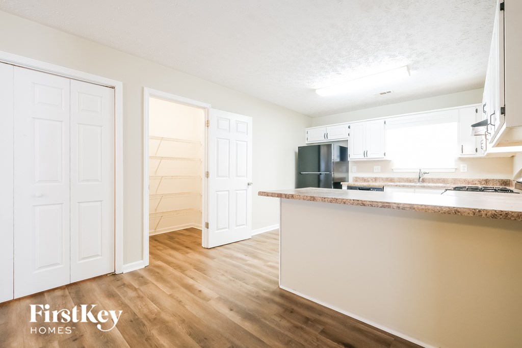 A kitchen with white cabinets and a wooden floor.