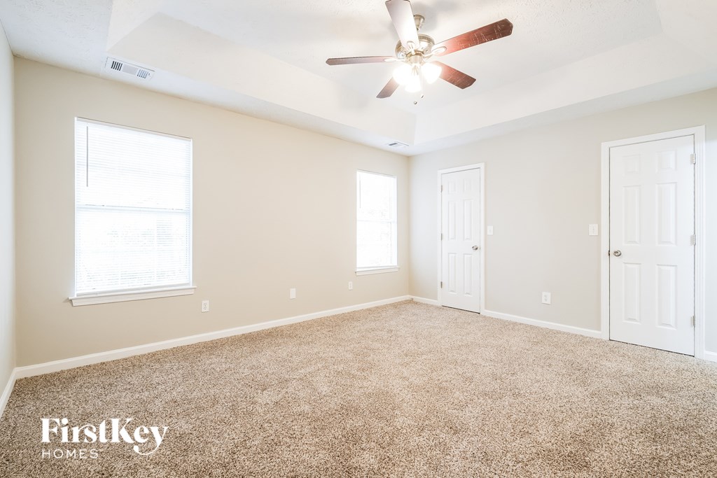 A spacious room with a carpeted floor and a ceiling fan.