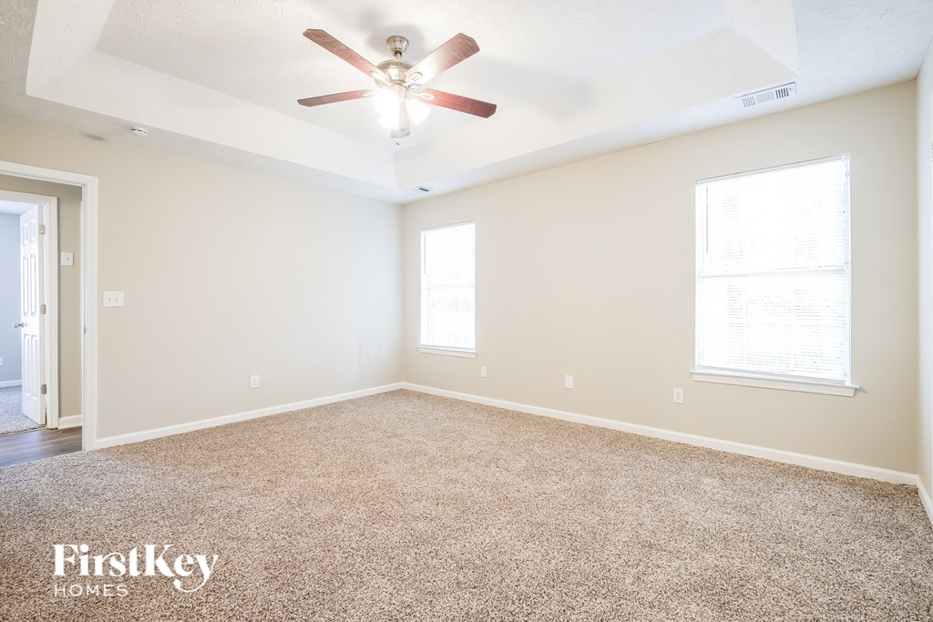 A spacious room with a carpeted floor and a ceiling fan.