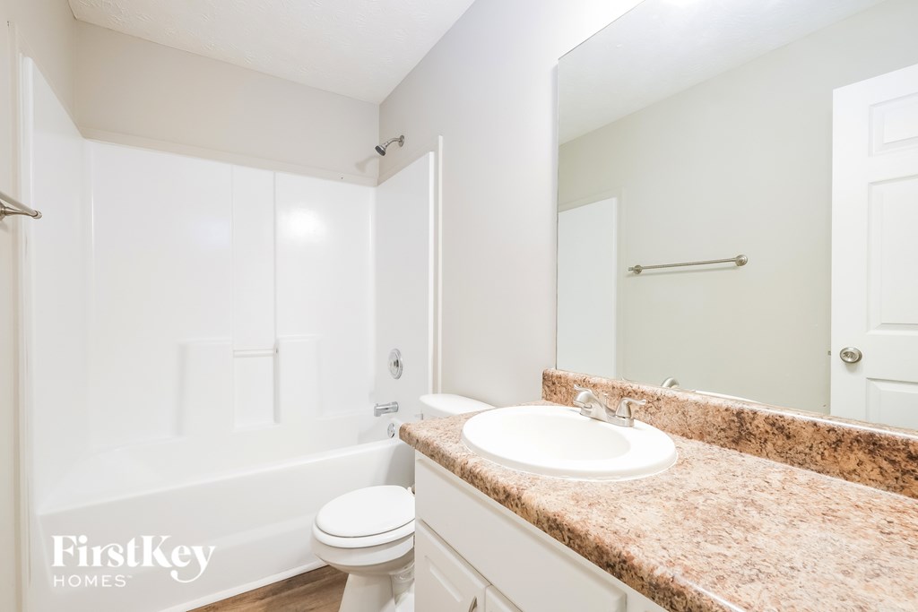 A white bathroom with a marble countertop and a white toilet.