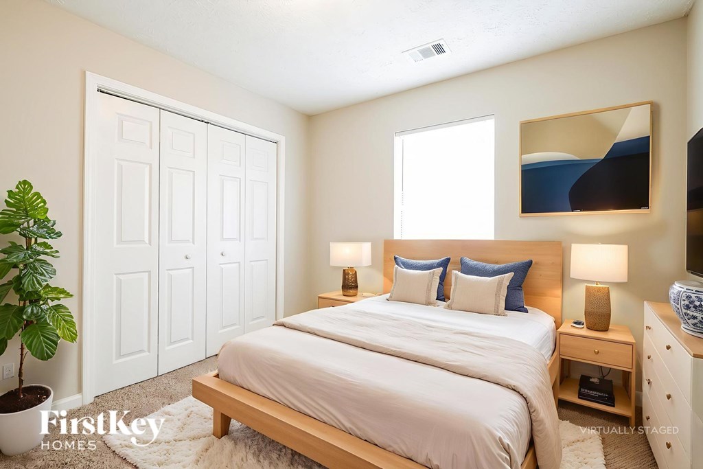 A bedroom with a bed, nightstands, and a plant.