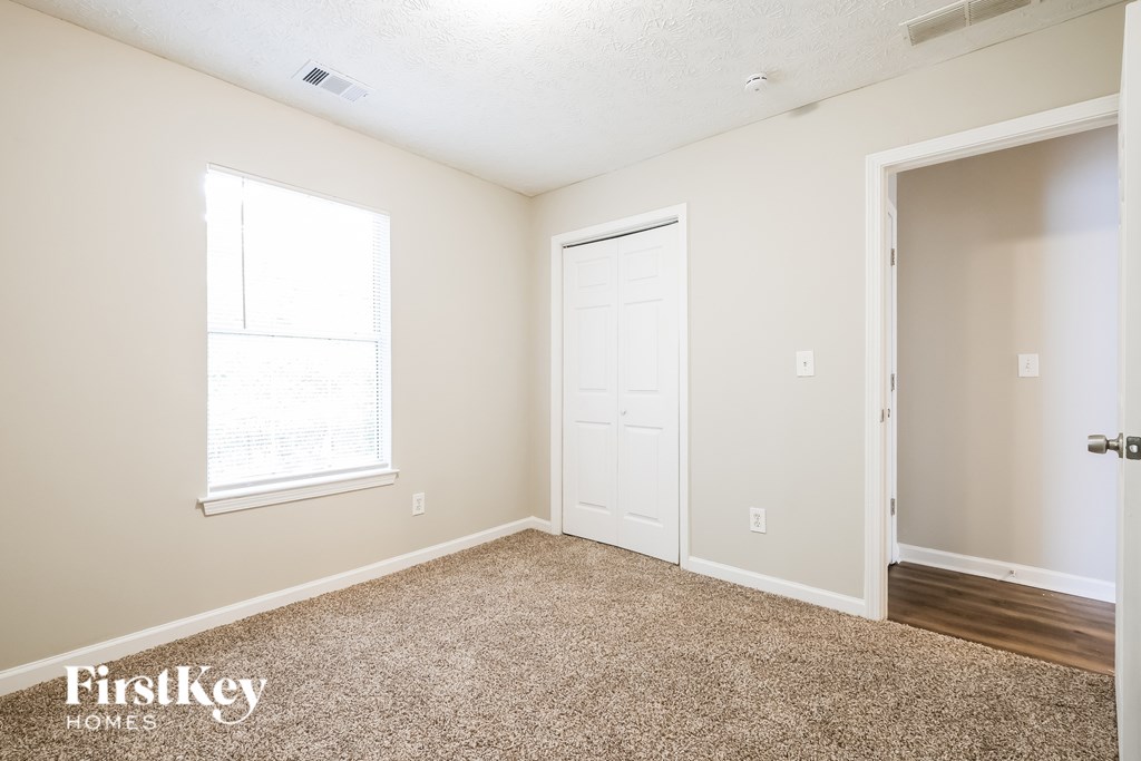 A room with a carpeted floor, a door, and a window.