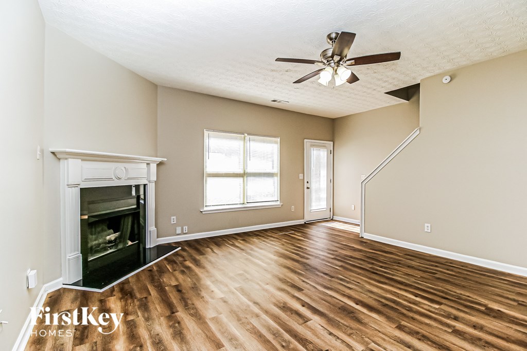 A spacious room with a fireplace and wooden floors.