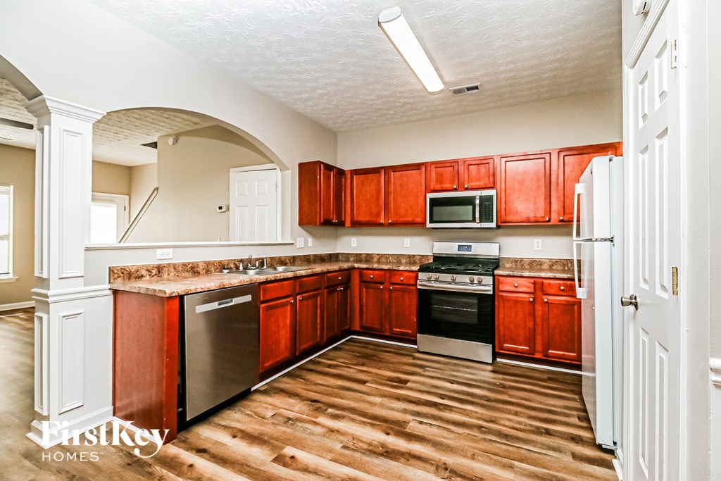 A kitchen with wooden floors and red cabinets.