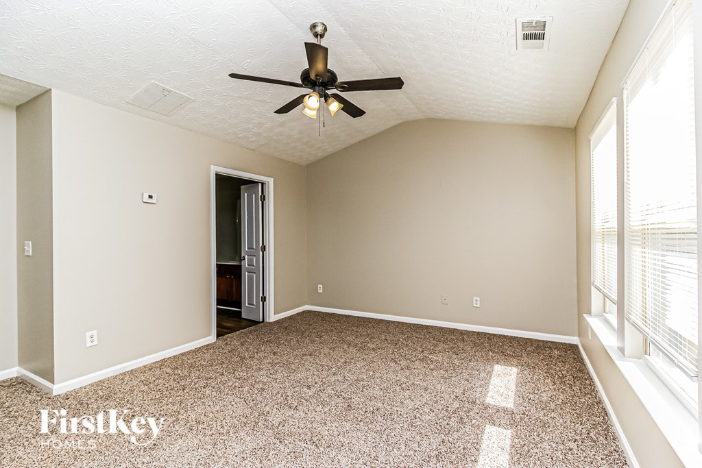 A room with a ceiling fan and a door leading to a balcony.