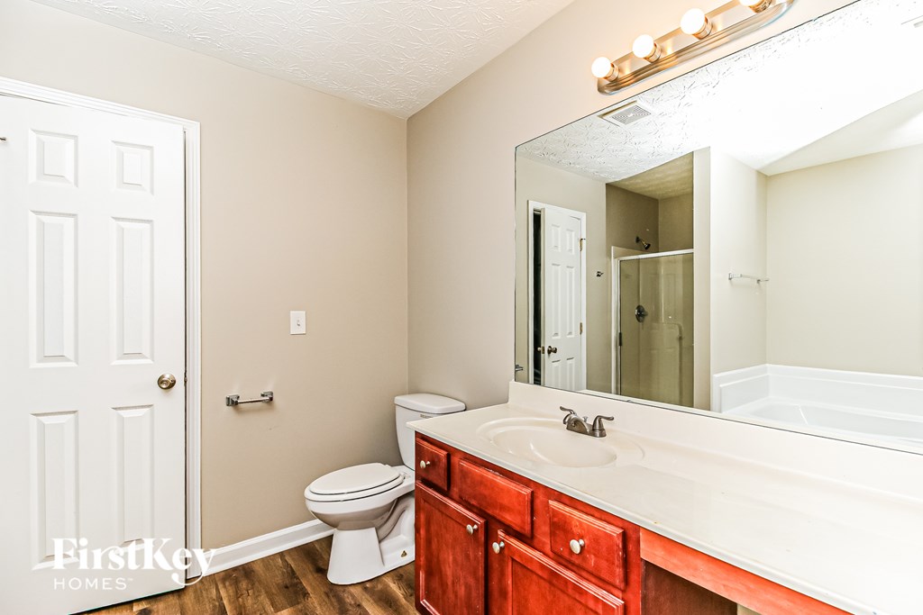 A bathroom with a toilet, sink, and mirror.