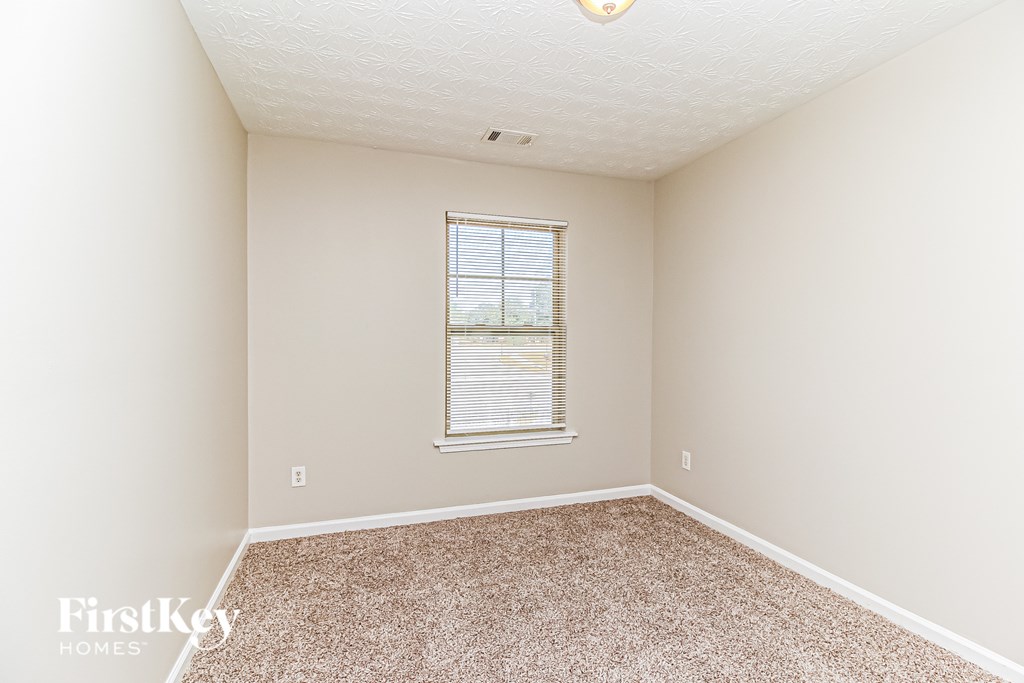 A room with a carpeted floor and a window with blinds.