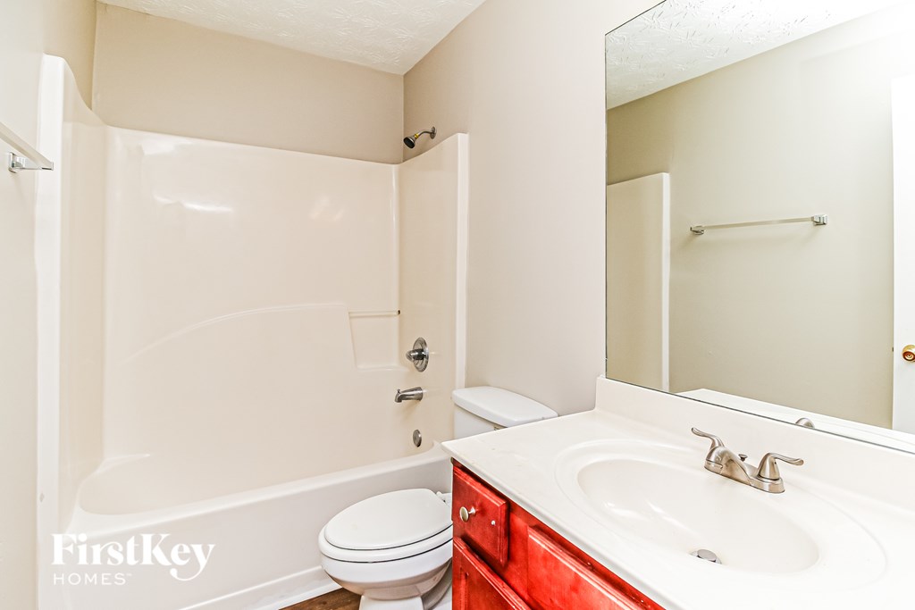 A white bathroom with a red vanity.