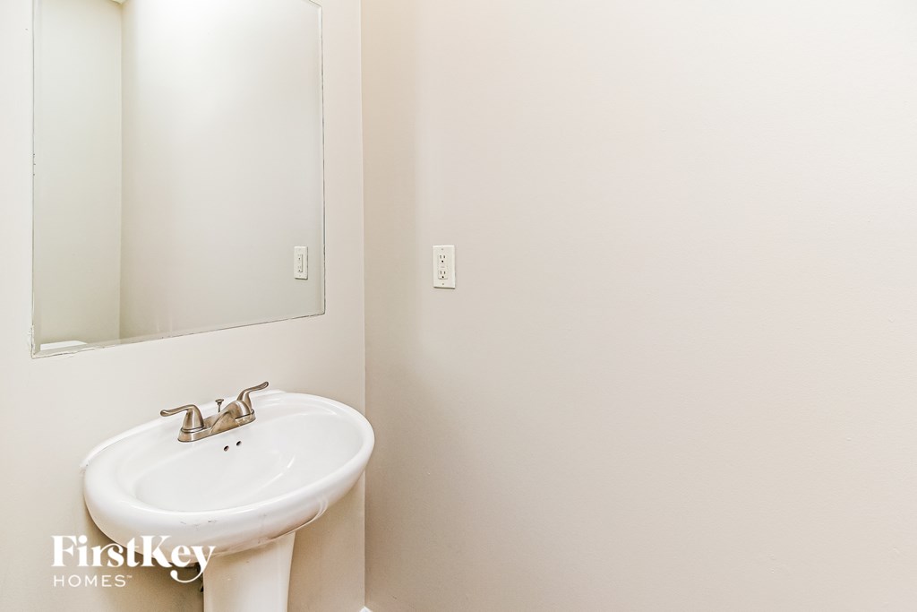A white sink in a bathroom with a mirror above it.