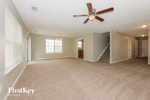 an empty living room with a ceiling fan